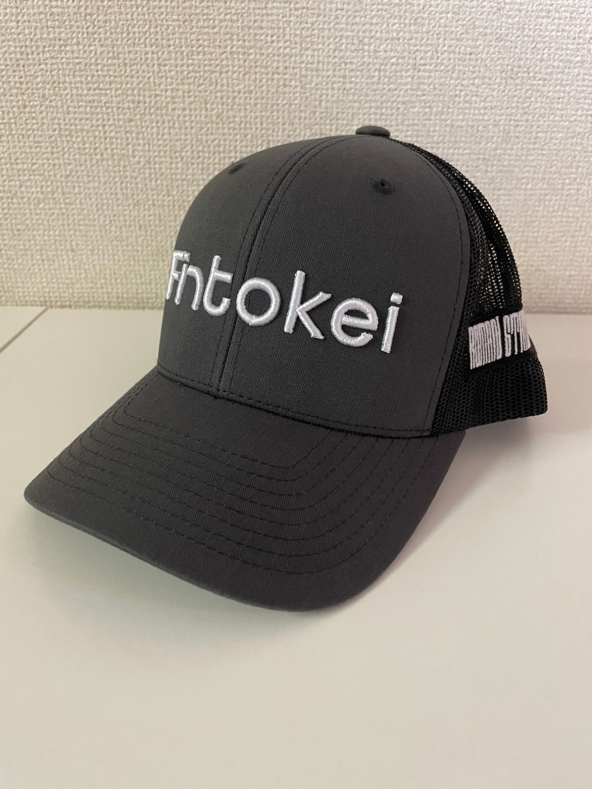 Fintokeiのロゴが白い立体刺繍で入ったダークグレーのメッシュキャップ。トレーダー交流会でもらったグッズ